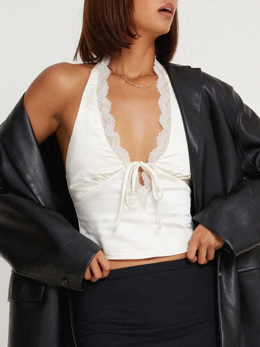 Woman wearing a white lace top and black leather jacket against a plain background